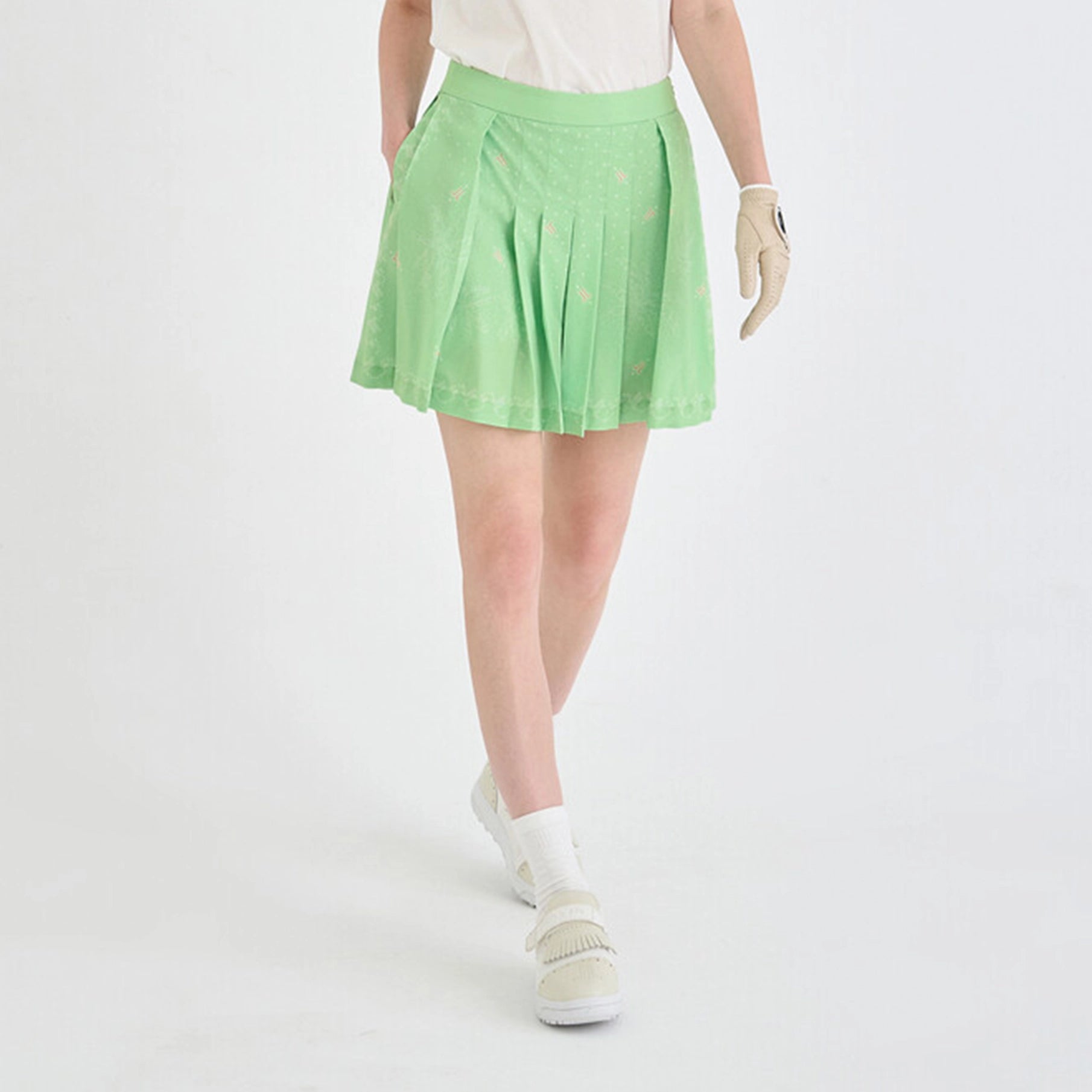 Person wearing a light green pleated skirt on a white background