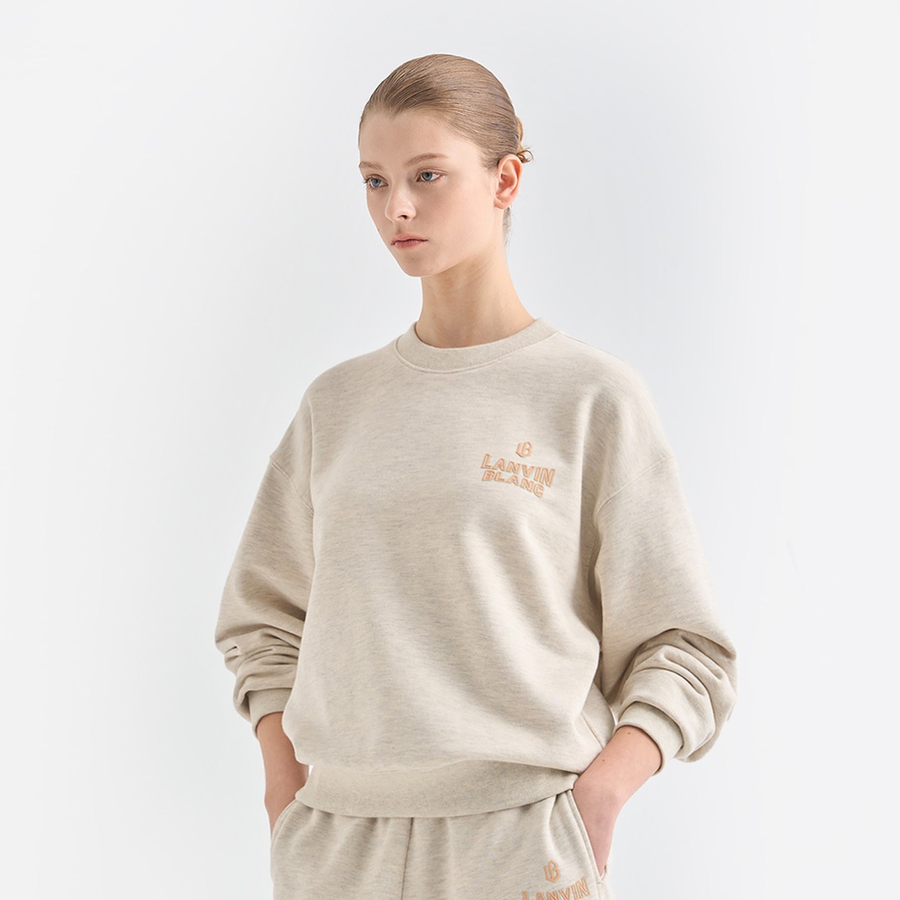 Person wearing a beige sweatshirt with text on a light gray background
