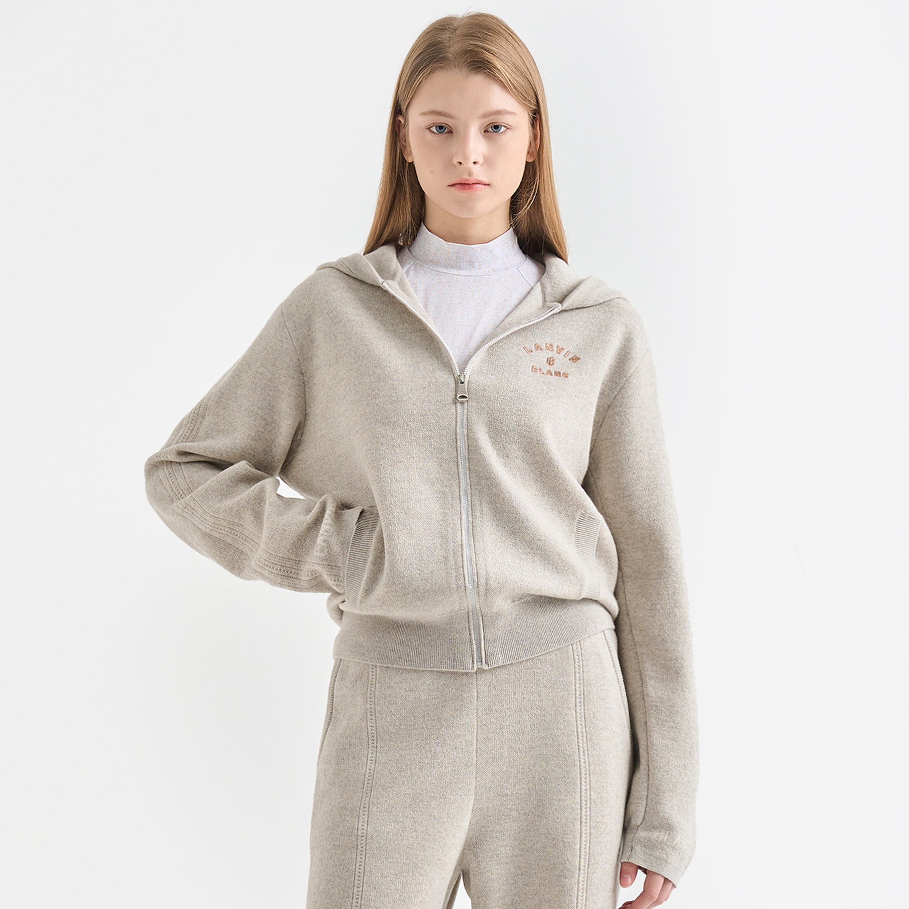 Person wearing a beige tracksuit with a white background