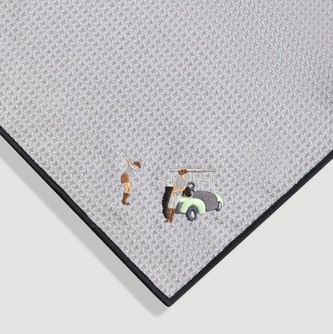 Close-up of gray magnetic golf towel showing textured fabric with embroidered golfer and golf cart detail - Laclavi Golf