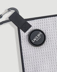Close-up of gray golf towel corner with carabiner clip and round black Laclavi Golf magnetic marker - Laclavi Golf