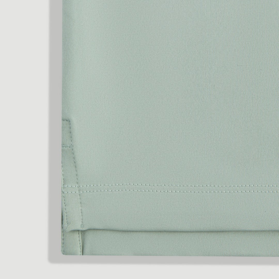 Green men's cowboy performance polo shirt hem close-up showing fabric texture and double-stitch detail - Laclavi Golf