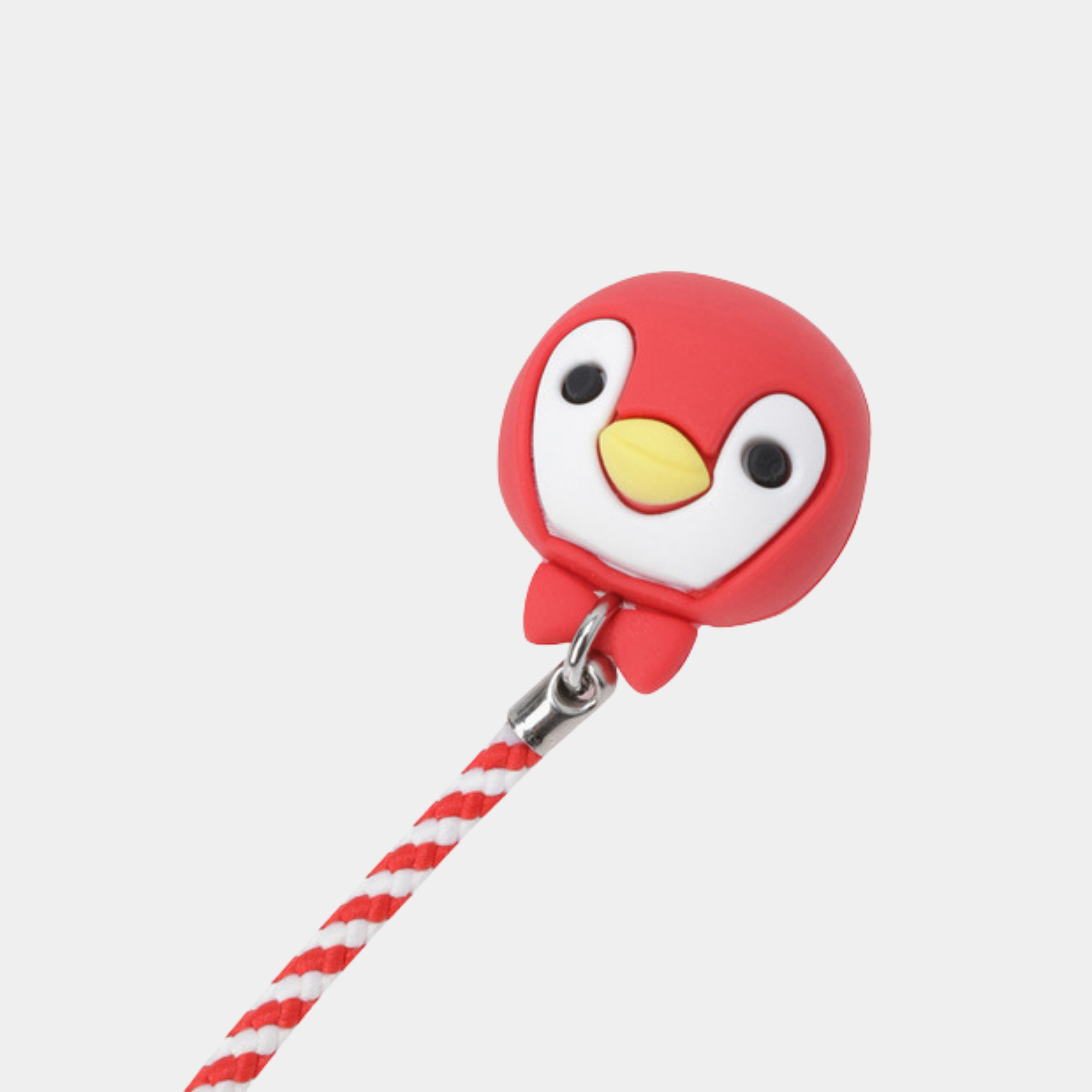 A red penguin-shaped tee holder with a yellow beak, white face, and black eyes, attached to a red-and-white striped cord on a light gray background.