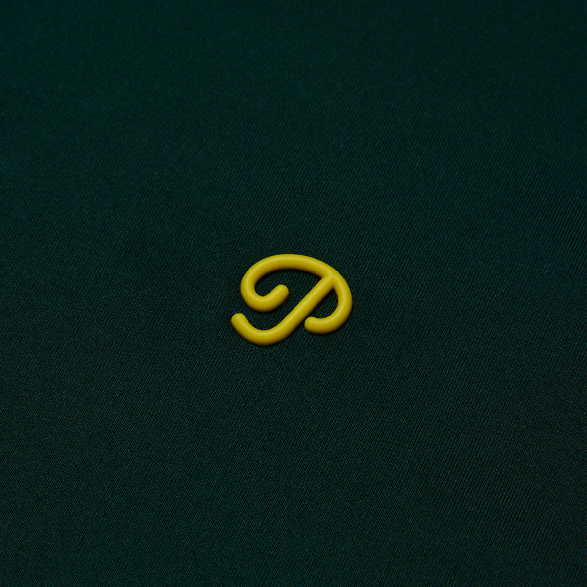 Close-up of the green polo’s textured fabric featuring a yellow logo.