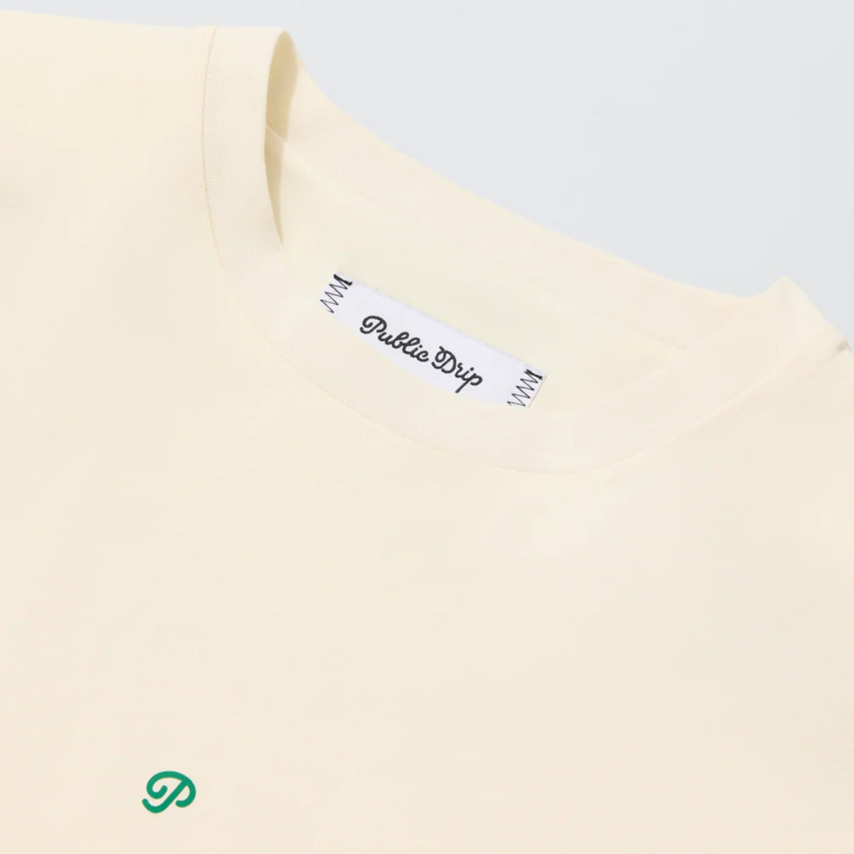 Close-up of the cream Swing Shirt’s lightweight performance fabric with the tag. 