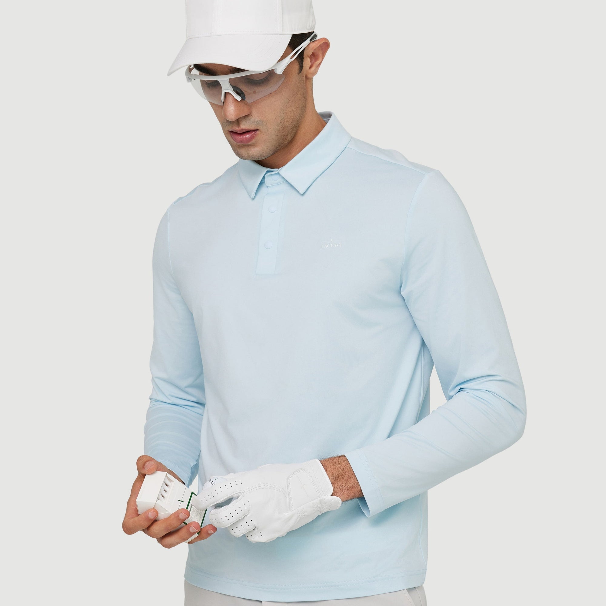 Golfer in light blue polo and white cap holding premium white golf tees while wearing a golf glove - Laclavi Golf