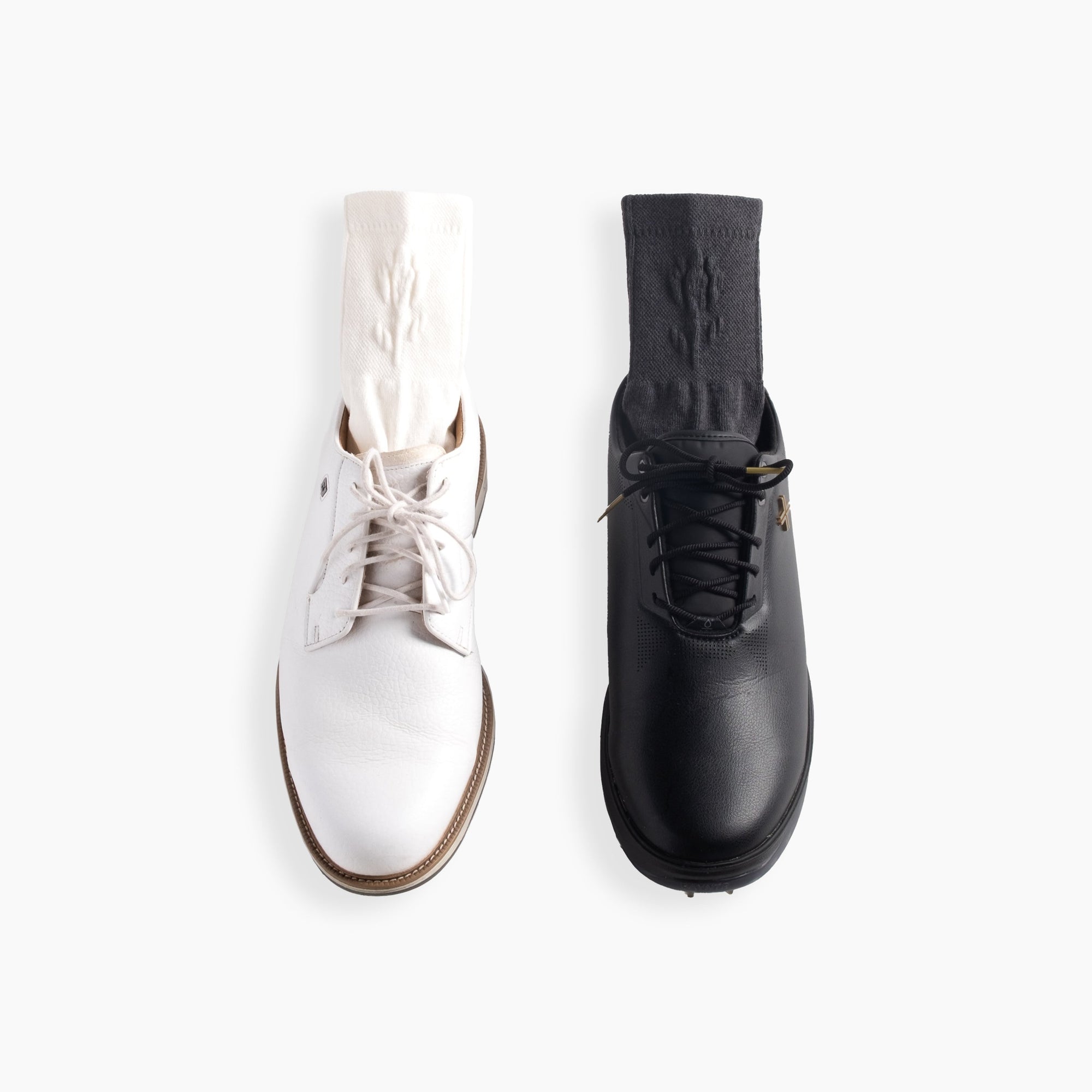 Two quarter socks styled with golf shoes, one in cream with a white shoe and one in gray with a black shoe, shown front view. Embossed Quarter Socks - Gray - Erthe Golf