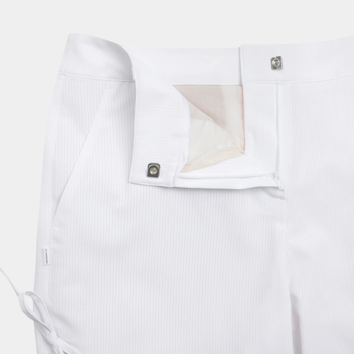 Close-up of white tailored trousers showing the waistband, button closure, and front fly area on a light neutral background.