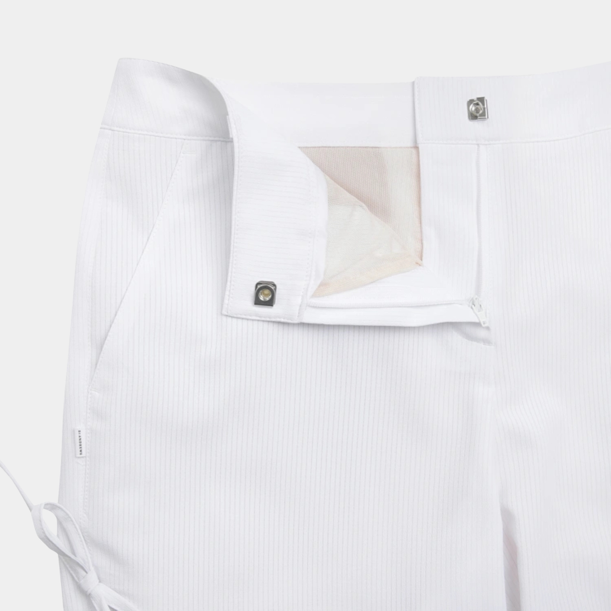Close-up of white tailored trousers showing the waistband, button closure, and front fly area on a light neutral background.