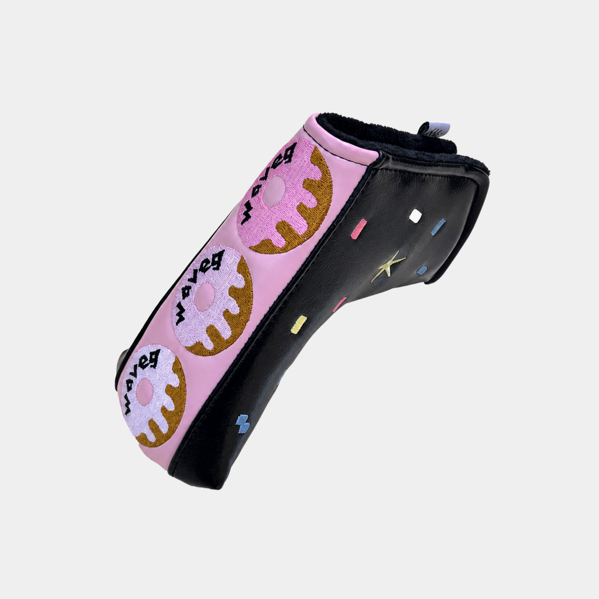 A pink and black golf club headcover featuring a playful donut pattern with the words 'we love donuts' and colorful sprinkle accents, shown on a light gray background.